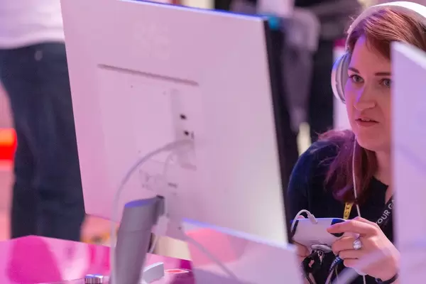 Woman plays with a Google Stadia controller in front of a white monitor at Gamescom trade fair in Cologne, Germany
