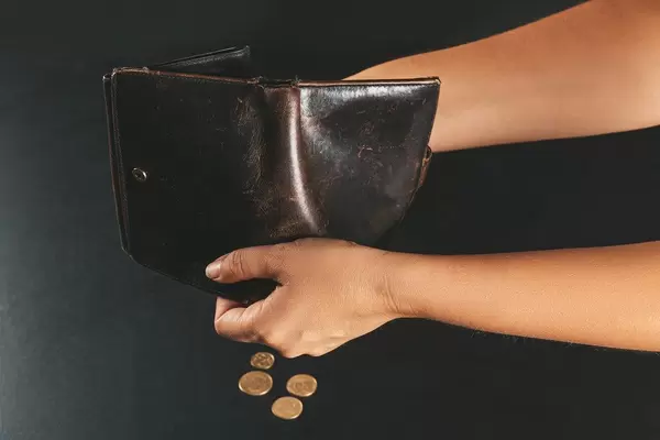 Woman pouring coins from wallet, concept of financial constraints, poverty