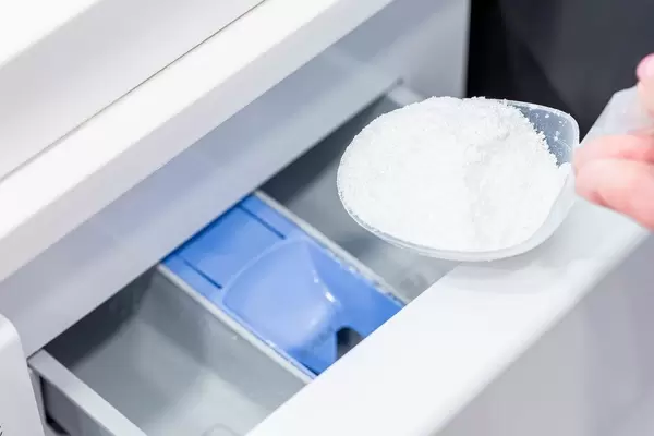 Woman pouring washing powder into the washing machine (Flip 2019)