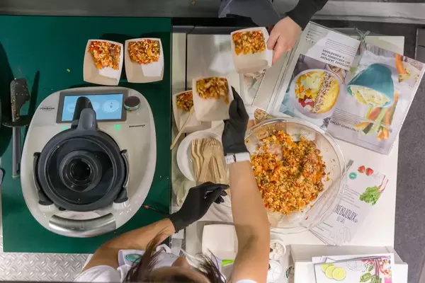 Woman prepares vegetable meal for tasting with the Thermomix TM6 cooker machine