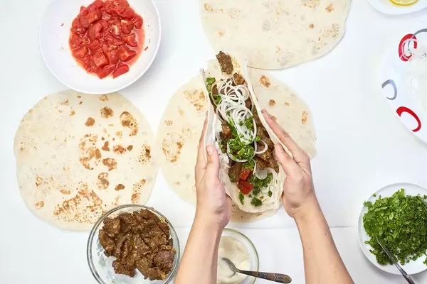 Woman preparing meat and vegetables based shawarma