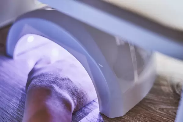 Woman puts hand into led uv lamp for curing nailpolish