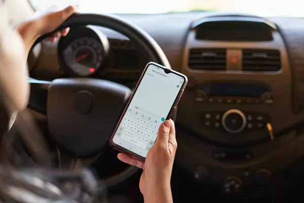 Woman sending message from a smartphone while driving a car