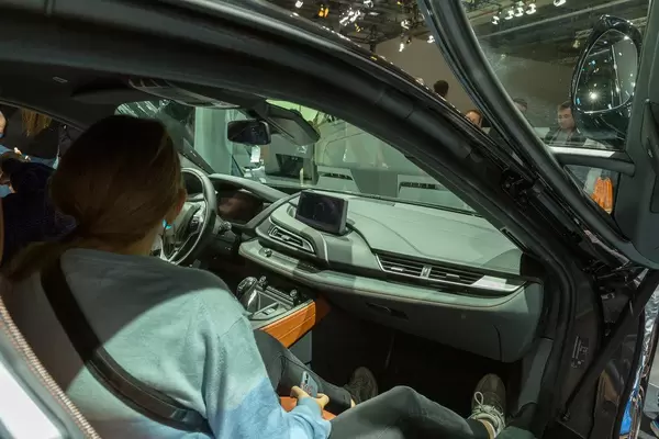 Woman sits inside the limited hybrid car BMW i8 Ultimate Sophisto Edition to look over the interior