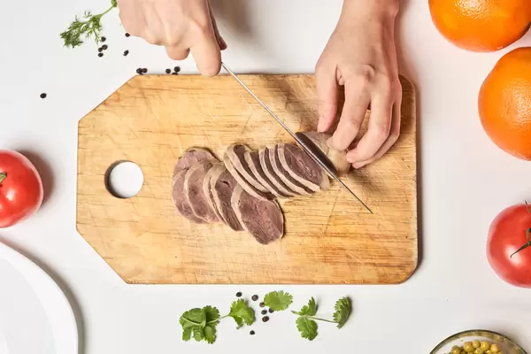 Woman slicing homemade horse meat sausage, also known as Kazy