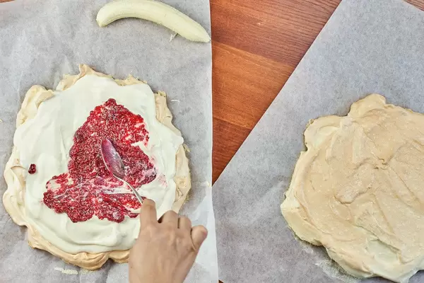Woman smearing raspberry jam on the sweet cake