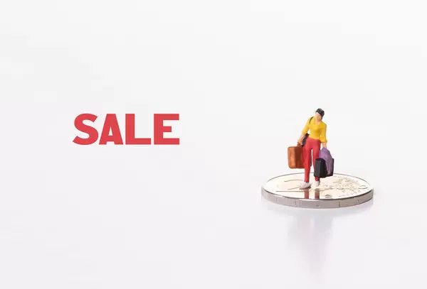 Woman standing on 2 Euro coin with Sale text