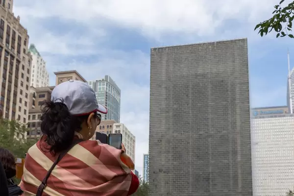 Woman takes a photo with her smartphone at the Crown Fountain at Millennium Park in Chicago