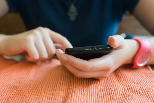 Woman with a smartphone in her hands at the table at home