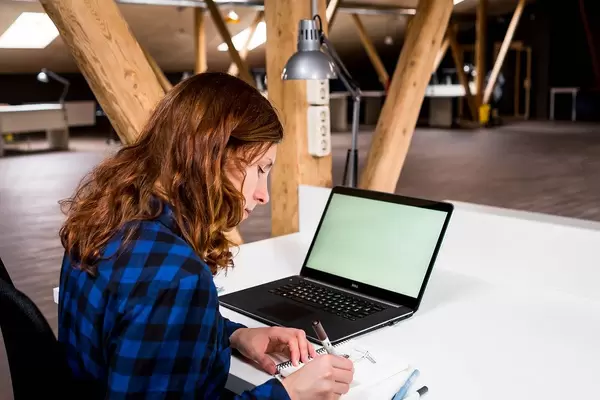 Woman works in an open space at a desk with a notebook