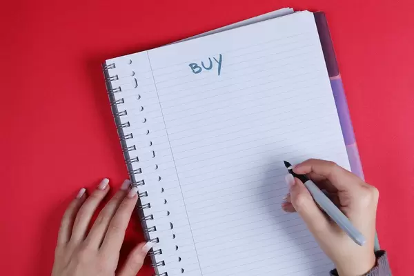 Woman writing Buy text on notebook, red background
