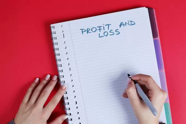 Woman writing Profit and Loss text on notebook, red background