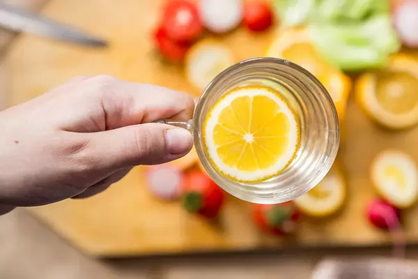 Woman's hand holding a glass of fresh lemon water (Flip 2019)