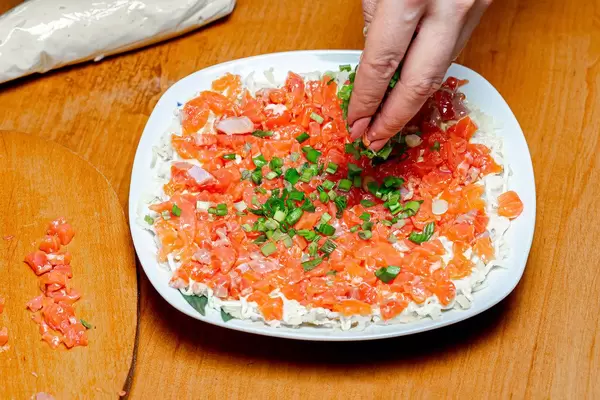 Woman's hand puts a young green onions on the salad (Flip 2020)
