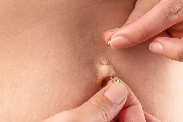 Woman's hands putting on her navel piercing