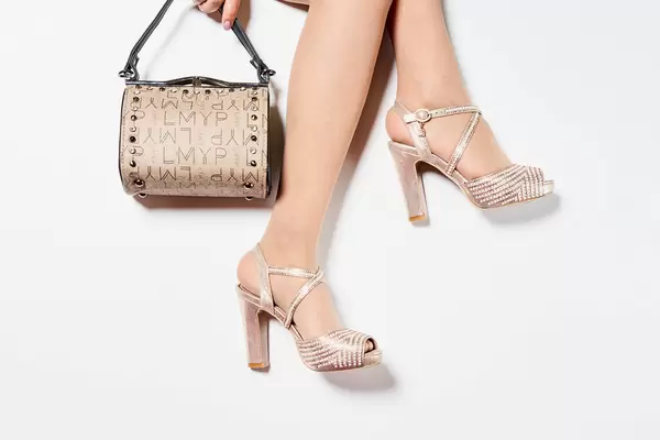 Woman's legs wearing high heel shoes and holding a handbag