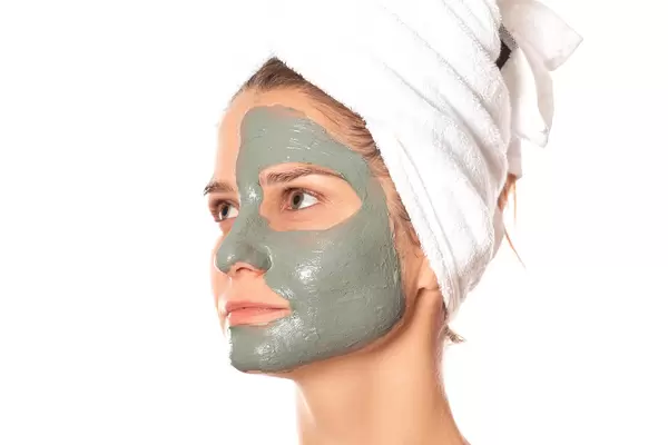 Women with a clay mask applied on their face with a white towel on their head