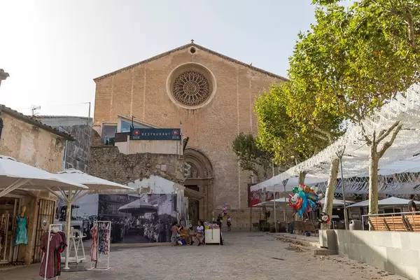 Women's clothes shop and street vendors in front of the Santa Maria dels Àngels church in Pollença