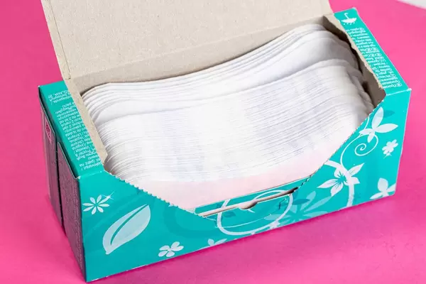 Women's daily pads in an open package on a pink background