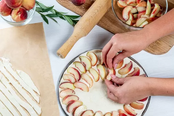 Women's-hands-lay-pieces-of-peaches-on-the-dough-Cooking-peach-pie.jpg