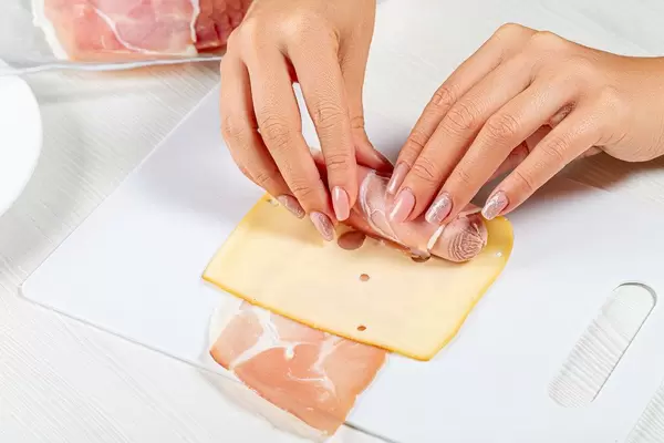 Women's hands wrap sausage in cheese and bacon (Flip 2019)