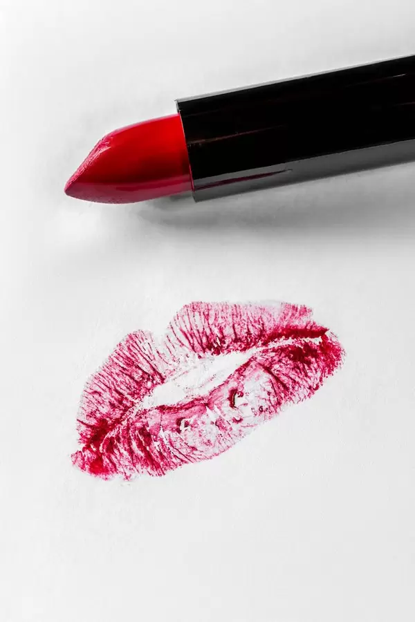 Women's red lipstick and the imprint of lips on a white background