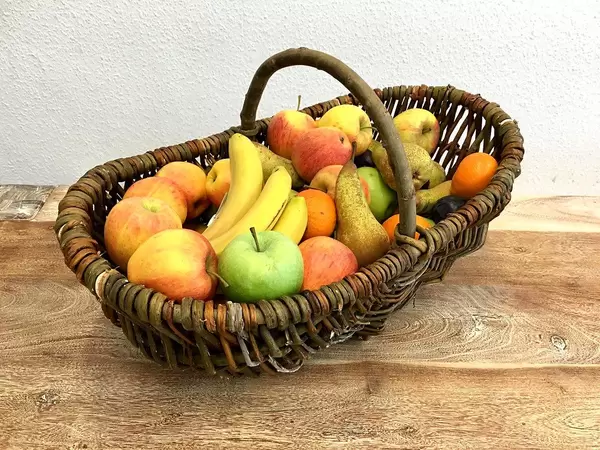 Wooden basket with fresh different fruits on a wooden table