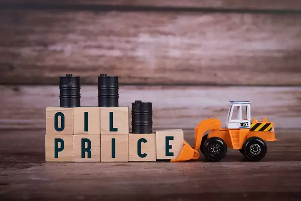 Wooden blocks with Oil Price text, oil barrels and bulldozer