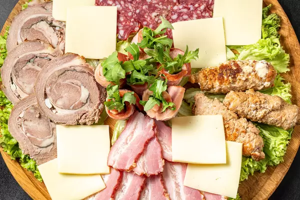 Wooden board with meat, salami and cheese cuts