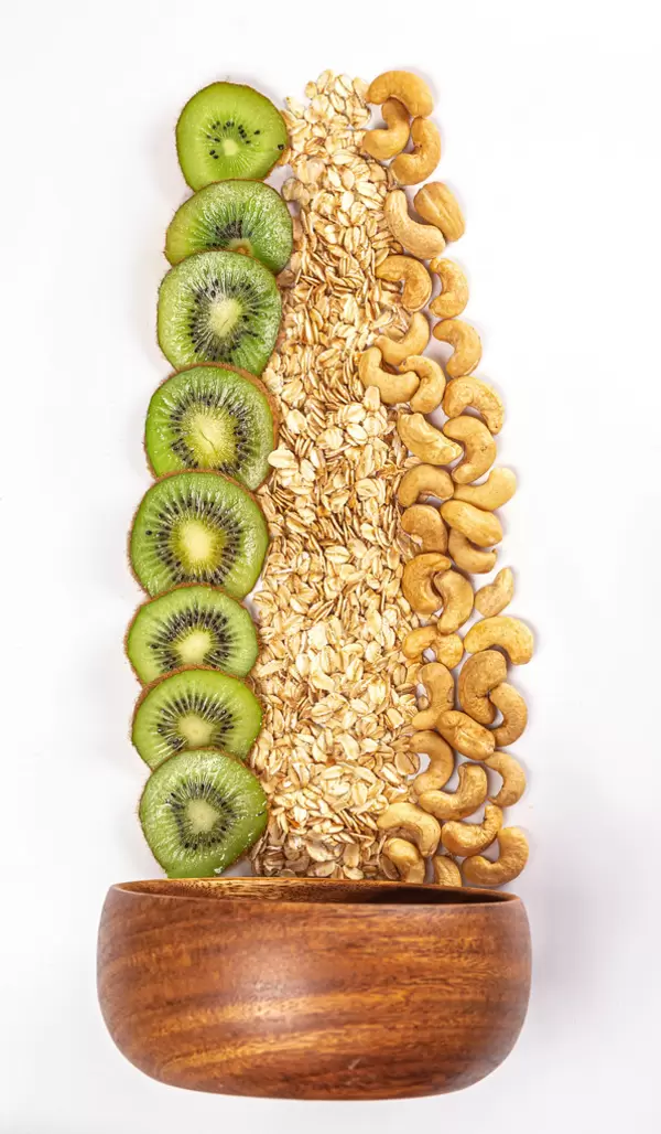 Wooden bowl with oatmeal, kiwi and cashew nuts, ingredients for a healthy breakfast
