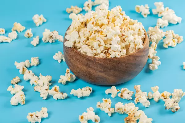 Wooden bowl with popcorn on a blue background