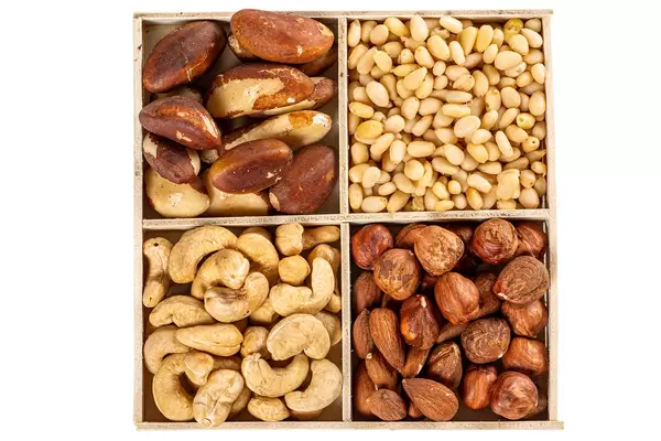 Wooden box with brazil nuts, cashews, pine nuts and hazelnuts, top view