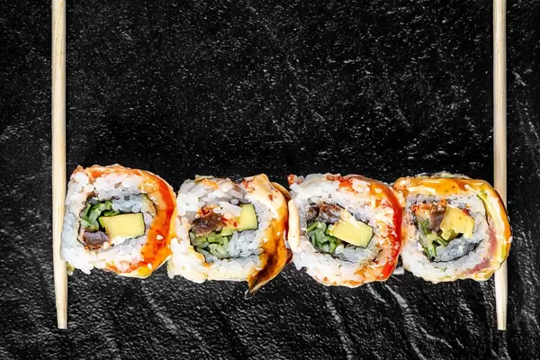 Wooden chopsticks and sushi Rainbow dragon on a black tray