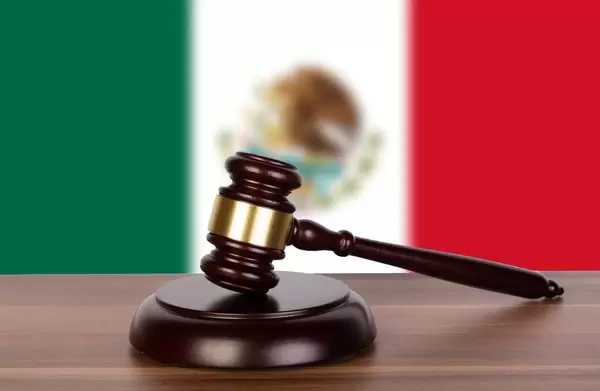 Wooden gavel and flag of Mexico