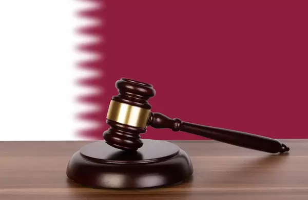 Wooden gavel and flag of Qatar