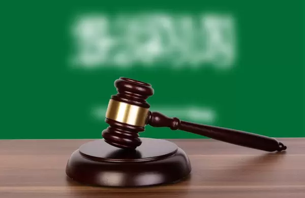 Wooden gavel and flag of Saudi Arabia
