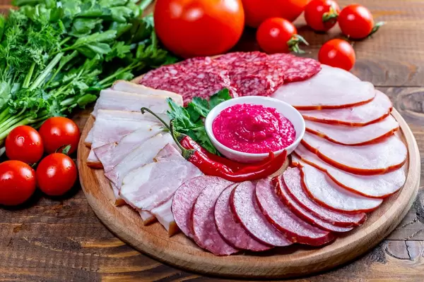 Wooden kitchen Board with sliced smoked sausages, salami, ham and meat with sauce on wooden table (Flip 2019)