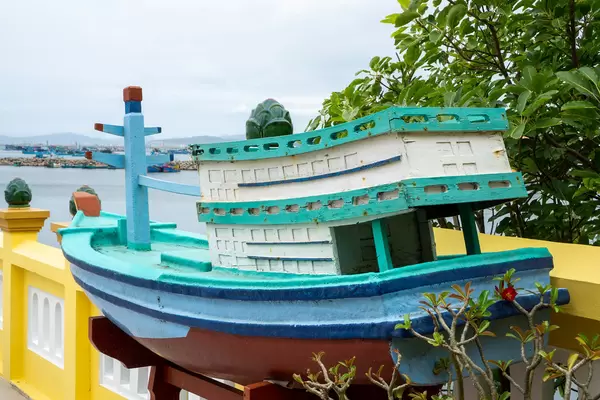 Wooden Miniature Fishing Boat at Dinh Cau Shrine with Mountains and Harbour in the Background in Phu Quoc, Vietnam