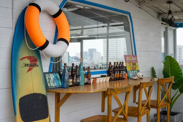 Wooden Outdoor Bar with Surfboard, Life Buoy, Beer Bottles and other Decorations at a Rooftop Restaurant in Saigon, Vietnam