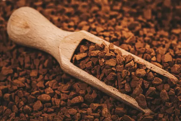 Wooden scoop with granules of instant coffee close-up
