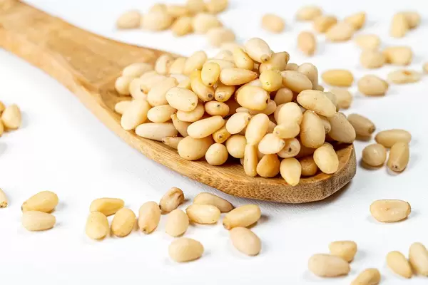 Wooden spoon with pine nuts on a white background (Flip 2020)