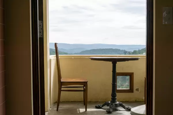 Wooden Table and Chair on a Balcony with Scenic Mountain View in the Background at Dreamers Home and Coffee in Dalat, Vietnam