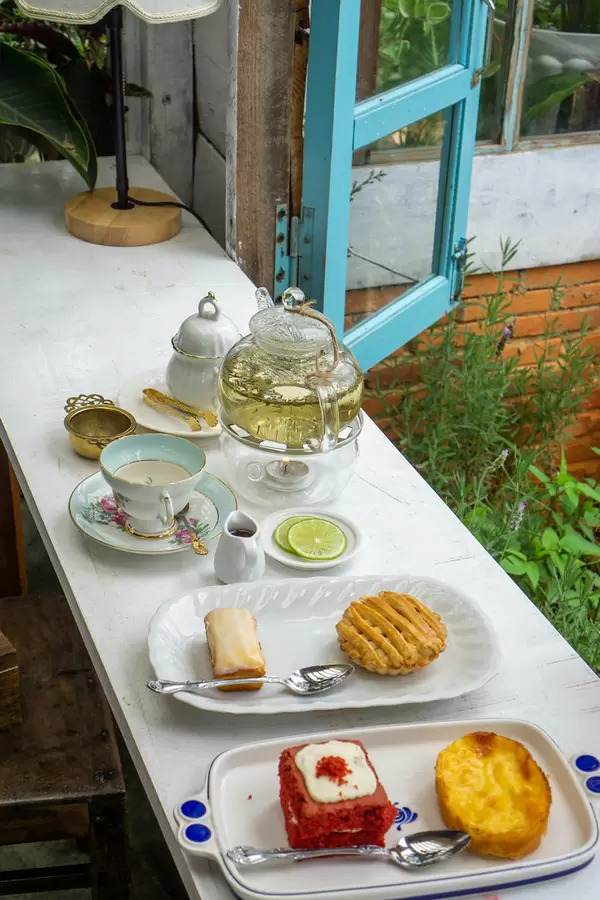Wooden Table with Glass Tea Pot, Ceramic Tea Cup, Cakes and Pastry in a Bakery