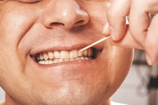 Wooden toothpick and white healthy teeth of a man (Flip 2019)