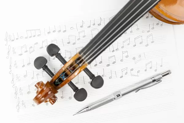 Wooden Violin Neck with Notes on the sheet music and Pen above white background