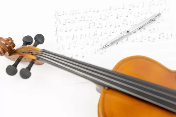 Wooden Violin with Notes on the sheet music above white