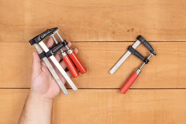 Woodworking F Clamps in the hand with wooden background