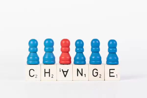 Word Change written on wooden blocks with pawns in various colors on white background