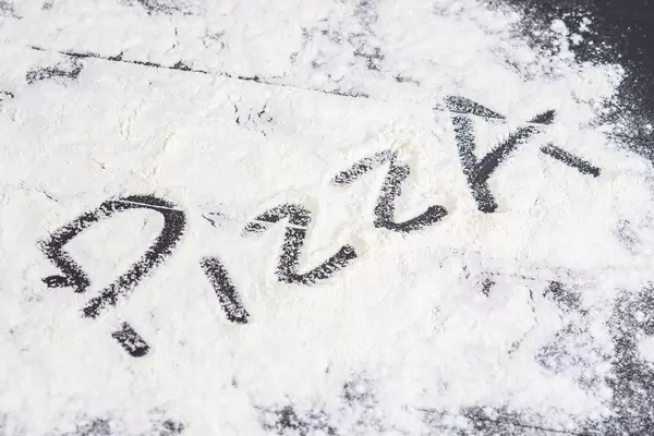 Word Pizza on the spilled flour on the black table