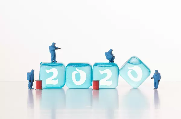 Workers in chemical protection clothes with ice cubes with 2020 text
